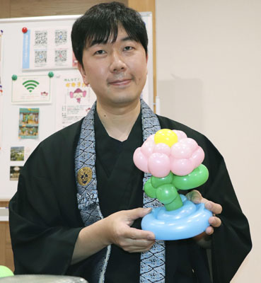 写真：自身が作ったハスの花のバルーンアートを手にする常高寺の加藤大地住職＝愛媛県今治市