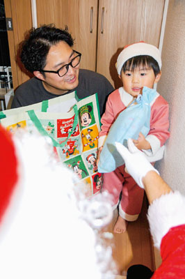 写真：突然のサンタ登場に驚きながらプレゼントをもらう子ども＝２４日午後５時５０分ごろ、豊浦町