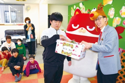 写真：にゃんまると吉田店長（右）から菓子を受け取る子どもたち＝放課後等デイサービスほくと