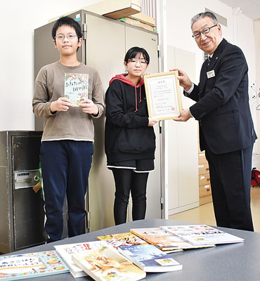写真：東小児童代表に図書を届ける川上参事（右）