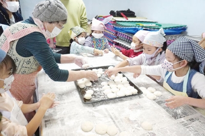 写真:大人から教わりながら、餅を小さく丸める子どもたち(提供写真)