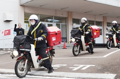 写真：年賀状をバイクに積んで出発する配達員ら＝１日、室蘭郵便局