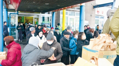 写真:店の前で福袋を受け取る市民ら