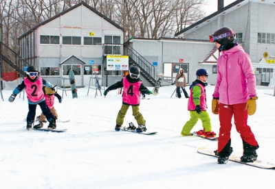 写真：ゲレンデでインストラクターから指導を受ける参加者たち