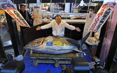 写真:「初競り」最高値の5億1030万円で競り落とされた青森県大間産のクロマグロとポーズをとる「喜代村」の木村清社長(中央)=5日、東京都内