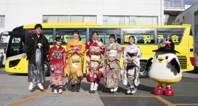 写真：「はとバス二十歳を祝う会」で、記念写真に納まる２０歳になるガイドの女性と整備士の男性＝６日午前、東京都大田区