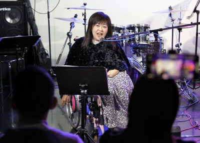 写真：車いすでステージに立ち、ハルウララへの感謝を歌に込める田中恵子さん＝２０２５年１２月、東京都千代田区