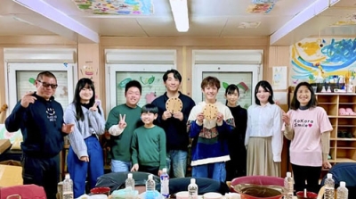 写真：支援した子どもたちと記念撮影する「こころスマイルプロジェクト」の志村知穂代表理事（右端）と遠藤伸一理事（左端）＝２０２５年３月、宮城県石巻市（こころスマイルプロジェクト提供）