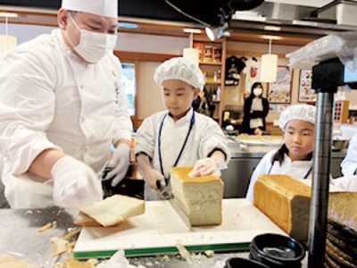 写真：パンの耳をカットする子ども（提供写真）