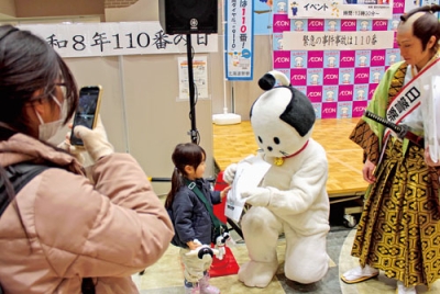 写真：「ニャンまげ」から啓発物を受け取る子ども