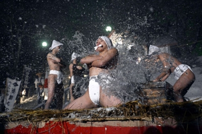 写真：神事「寒中みそぎ」で、冷水を浴びて身を清める下帯姿の「行修者」＝１３日夜、北海道木古内町の佐女川神社