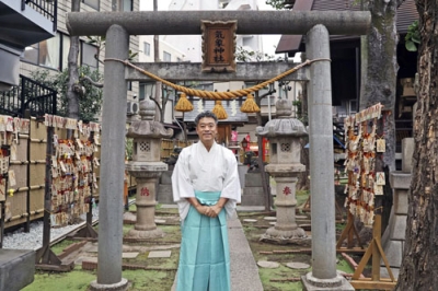 写真:「気象神社」の前に立つ高円寺氷川神社禰宜の紺谷大進さん=2025年11月、東京都杉並区