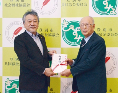 写真：仲川会長に寄付金を手渡す佐藤さん（右）