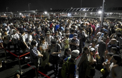 写真：大阪・関西万博会場にアクセスする地下鉄がトラブルで運転を見合わせ、会場のゲート前で並ぶ人たち＝２０２５年８月、大阪市此花区の夢洲