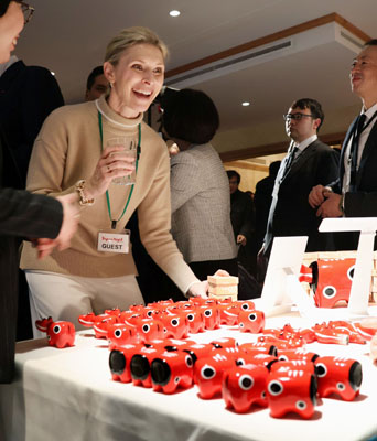 写真:福島県の郷土玩具「赤べこ」を前に笑顔を見せる来場者=21日、スイス東部ダボス(共同)