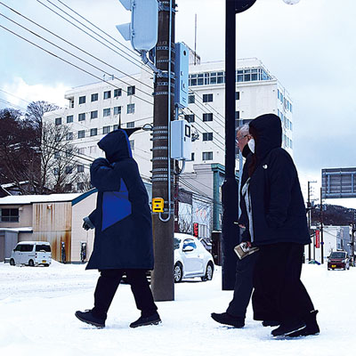 写真：雪で真っ白に染まった路上を歩く市民ら＝２２日午後０時２５分ごろ、室蘭市海岸町