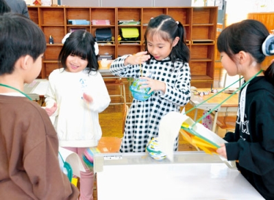 写真：在校生が作ったおもちゃで遊ぶ体験入学の子どもたち（左から２人目と３人目）