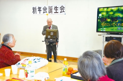 写真：余興でカラオケを披露する会員