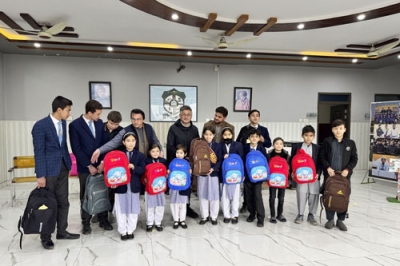 写真：贈られたかばんを手にするアフガン難民の子どもたち（前列）と今井さん（後列右から３人目）＝２０２５年１月、パキスタン・ペシャワル近郊（三方舎提供）