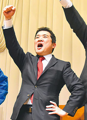 写真：拳を突き上げガンバロー三唱をする山岡氏