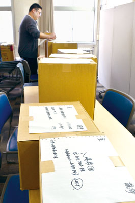 写真：急ピッチで投票所入場券をチェックする室蘭市選管職員