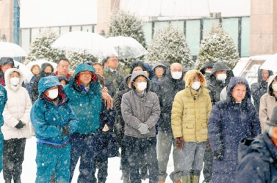 写真：雪が降る中、候補者の訴えに耳を傾ける有権者ら＝２７日午後１時４５分、登別市中央町