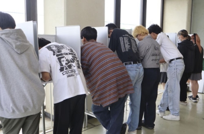 写真:2024年6月、高校で実施された東京都知事選の模擬投票で、候補者の名前を記入する生徒たち=東京都練馬区