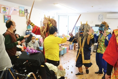 写真:福を願って自作の豆をぶつける利用者たち