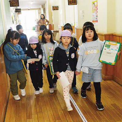 写真:1年生に手を引かれ校内を探検する園児たち