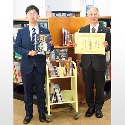 写真:感謝状を手にする林専務取締役(右)と児童書を持つ社員