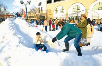 写真:雪の滑り台を楽しむ親子ら