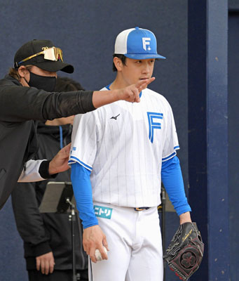 写真:ブルペンで新庄監督(左)の指導を受ける日本ハムの北山=名護