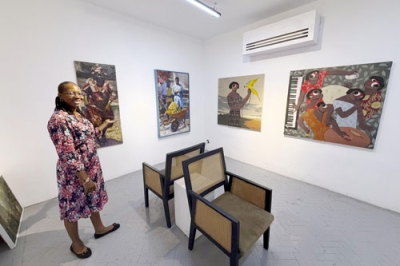 写真：ナイジェリア・ラゴスにある画廊に展示された絵画を紹介するケニー・マイケルさん＝２０２５年１２月（共同）