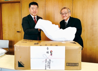 写真：フェースタオルを手渡す髙橋支部長（左）（提供写真）