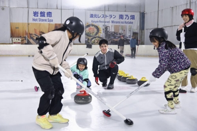 写真：カーリング体験会に参加した子どもたちと上地雄大さん（中央）＝２０２５年１１月、沖縄県南風原町