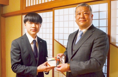 写真：奨学生の橋本さん（左）に記念品を贈る松本副会長
