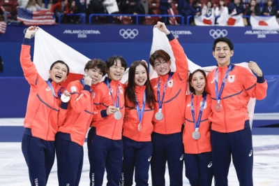 写真：団体で銀メダルを獲得し日の丸を掲げる（左から）坂本花織、佐藤駿、鍵山優真、吉田唄菜、森田真沙也、三浦璃来、木原龍一＝ミラノ（共同）