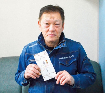 写真：会員に配布する商品券を手にする山田会長