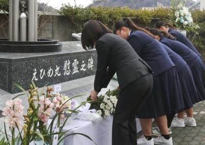 写真：えひめ丸事故から２５年となり、「追想の日」式典で慰霊碑に献花する宇和島水産高の生徒ら＝１０日午前、愛媛県宇和島市