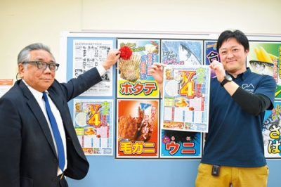 写真：４連覇を果たしたホタテのポスターに花を付ける金丸理事長（左）