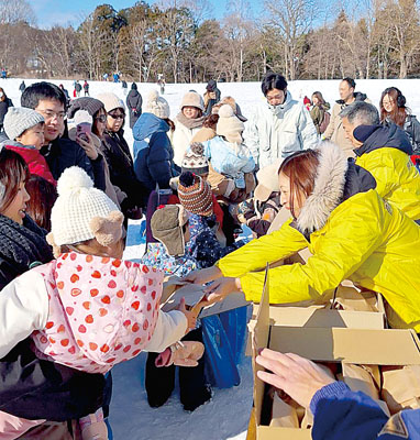 写真：伊達飲食店組合の菓子の配布に集まる雪まつり来場者ら（提供写真）