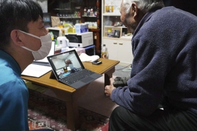 写真：患者の自宅でオンライン診療を見守る特定看護師の男性（左）＝２０２５年１２月、青森県東通村