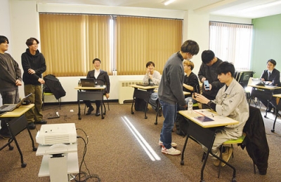 写真:今野課長(右)に紹介したツールの使い方を教える学生たち