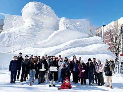 写真：大通会場の大雪像前で記念写真に納まる留学生ら（提供写真）
