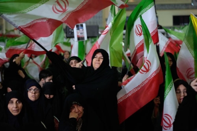 写真：１７日、イラン体制側がテヘランで催した反政府デモの死者の追悼式典で、国旗を振る女性ら（ＡＰ＝共同）