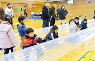 写真：ジェットヒーターを活用した簡易暖房設備で体を温める子どもたち