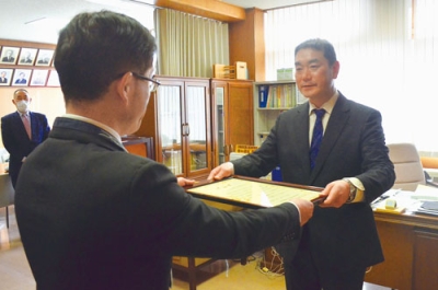 写真:髙橋局長から表彰状を受け取る鈴木校長(右)