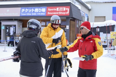 写真：スキー場を訪れた外国人スキー客に安全啓発をする長野県警の職員＝１月、長野県白馬村