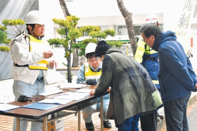 写真：訓練の一時集合場所となった洞爺湖文化センターで参加者の受け付けを行う町職員ら