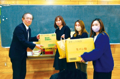 写真：平石校長（左）に雑巾を渡す郡司会長（左から２人目）